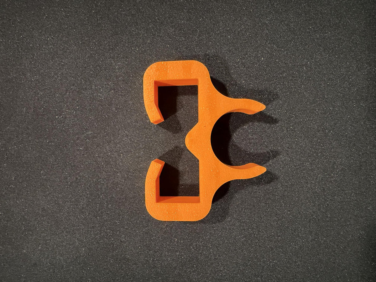 Orange trimmer line holder shown mounted on a string trimmer shaft