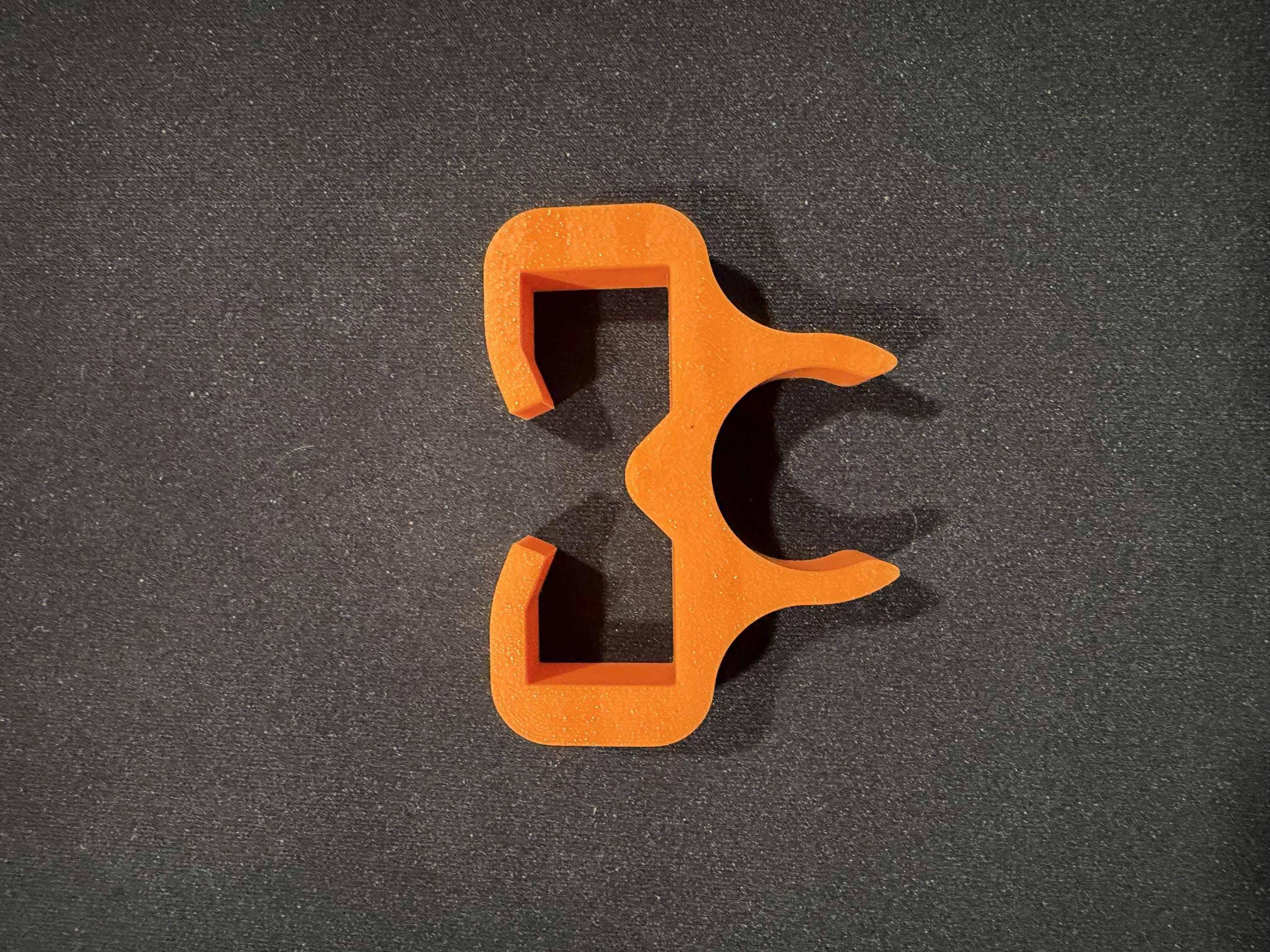 Orange trimmer line holder shown mounted on a string trimmer shaft