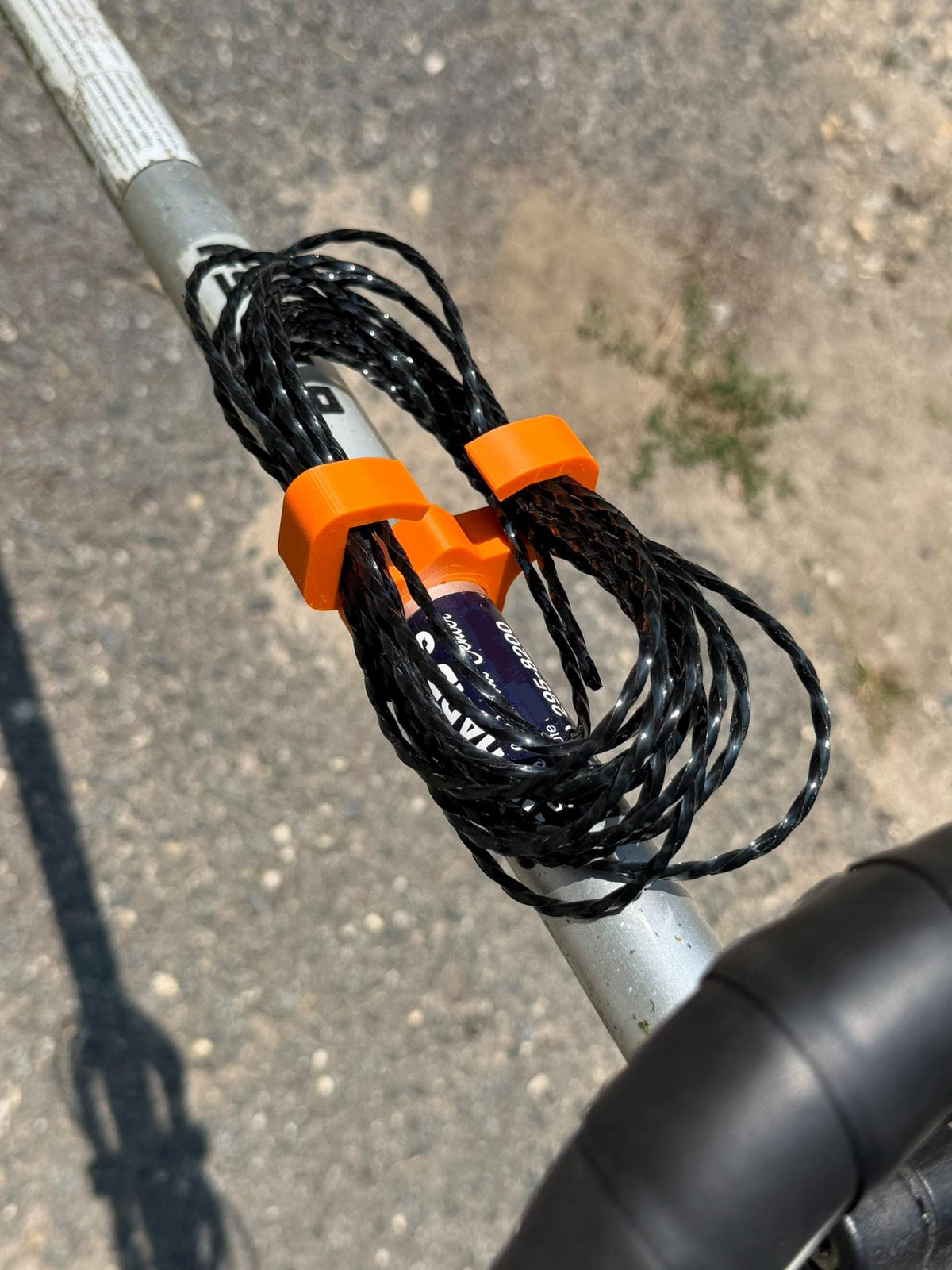 3D printed weed eater string holder clipped onto a trimmer shaft with spare line coil loaded